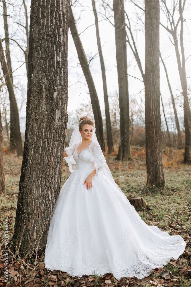 A woman in a white wedding dress stands in front of a tree. Concept of serenity and natural beauty, as the bride is surrounded by the peacefulness of the forest. The dress itself is elegant A woman in a white wedding dress stands in front of a tree. Concept of serenity and natural beauty, as the bride is surrounded by the peacefulness of the forest. The dress itself is elegant