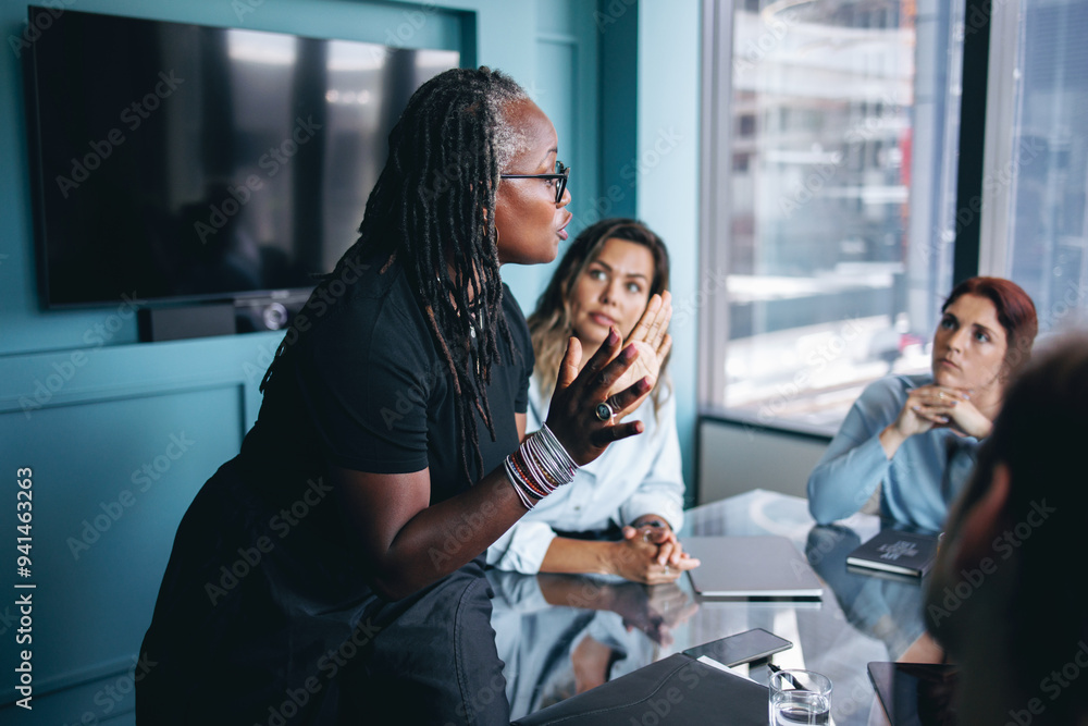© Jacob Lund - Mature black business woman discussing her strategy with her team in a boardroom