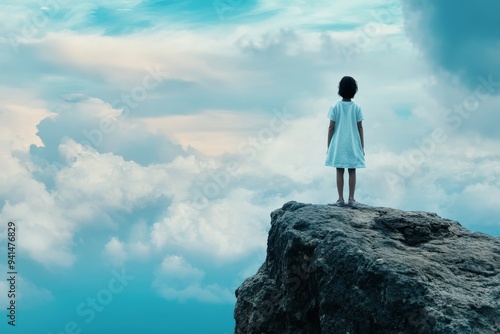 A young child stands on the edge of a rocky cliff overlooking a breathtaking expanse of clouds, representing adventure, courage, and the vastness of nature.