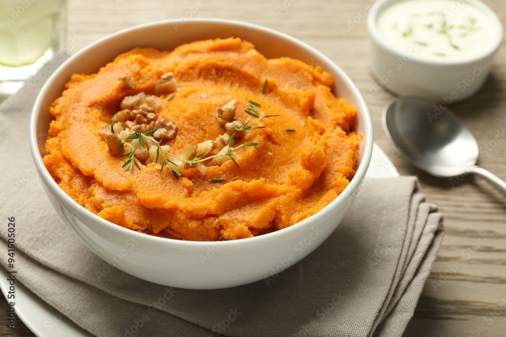 Delicious mashed sweet potatoes in bowl and spoon on wooden table, closeup Delicious mashed sweet potatoes in bowl and spoon on wooden table, closeup