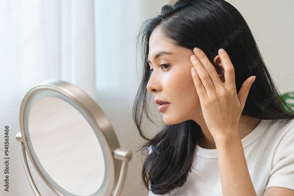 Anti aging beauty, happy asian young woman looking in mirror reflection at home, touching face skin satisfied with healthy moisturized, skin care treatment cosmetic for dry skin during morning routine Anti aging beauty, happy asian young woman looking in mirror reflection at home, touching face skin satisfied with healthy moisturized, skin care treatment cosmetic for dry skin during morning routine