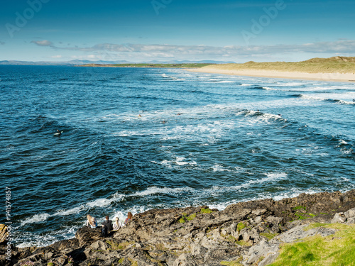 Stunning waves and sandy Bundoran beach in Ireland on warm sunny day. Popular tourist and surfers area. Blue cloudy sky. Irish landscape. Rich saturated color. Sport and travel theme. photo