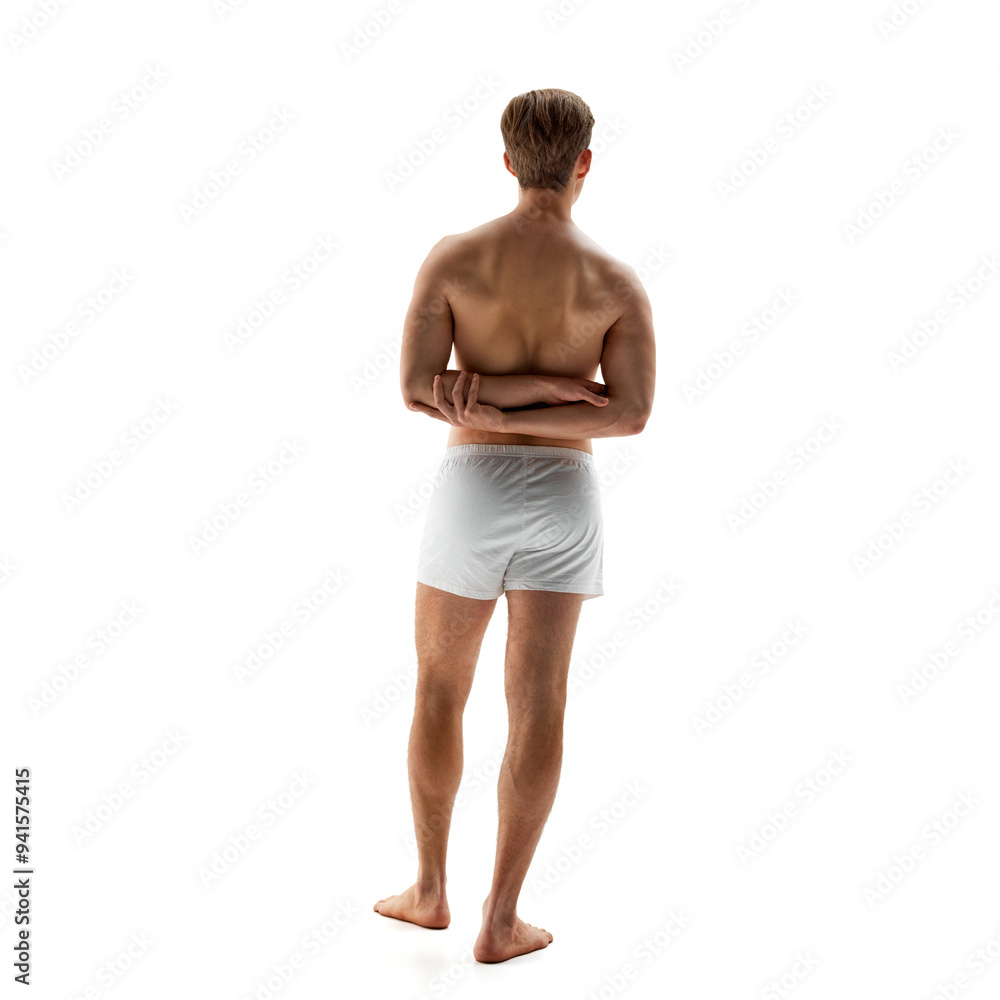 Rear view photo of young man in white underwear posing holding hands behind back against white studio background. Posture. Concept of male health, natural beauty people, fashion, self care. Rear view photo of young man in white underwear posing holding hands behind back against white studio background. Posture. Concept of male health, natural beauty people, fashion, self care.