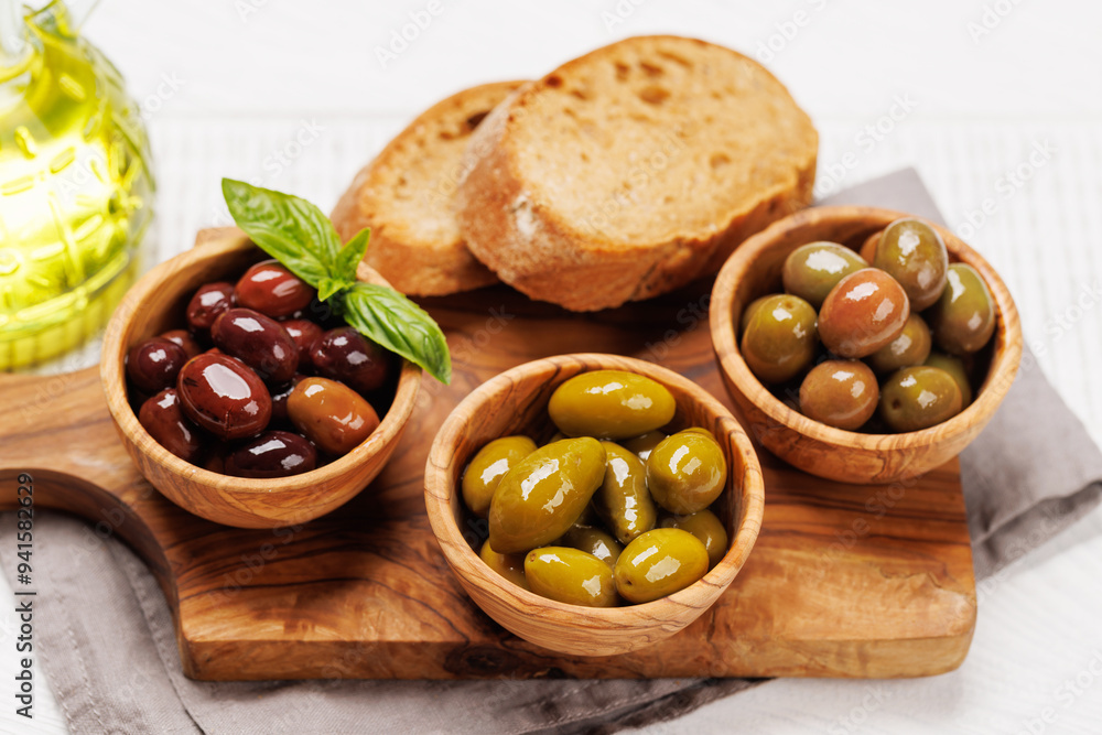 An assortment of various olives presented in a bowl, showcasing different colors, textures, and flavors An assortment of various olives presented in a bowl, showcasing different colors, textures, and flavors