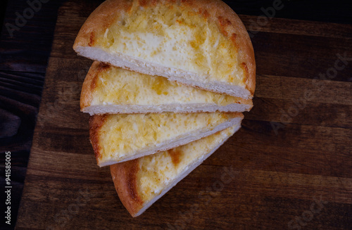 Khachapuri. Bun with cheese on a wooden background. Cheese pie. photo