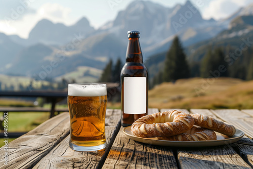 A close up of a bottle of beer with a blank mock up label on it and a glass of beer served together with brezels on the wooden table with mountains in the background photo