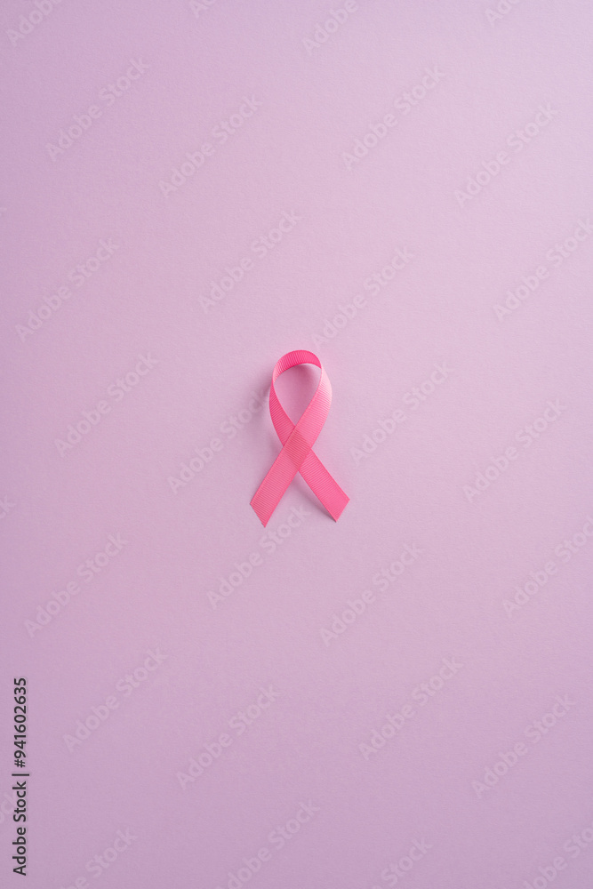 Pink vertical ribbon on a plain pink background representing breast cancer awareness, hope, and support Pink vertical ribbon on a plain pink background representing breast cancer awareness, hope, and support
