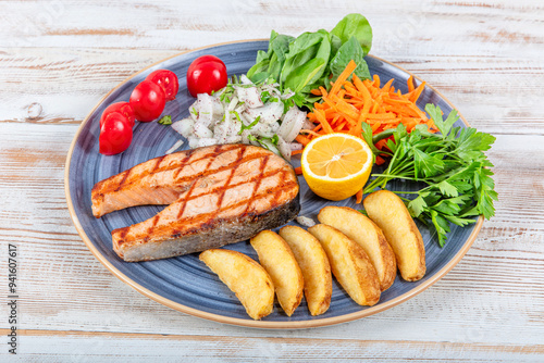 Turkish cuisine Grilled Salmon Steak with Thyme Branch. Grilled salmon steak with vegetables and tomato salad served on wooden table. Healthy food, keto diet food concept.Turkish name; Somon izgara. photo