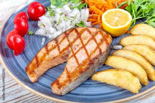 Turkish cuisine Grilled Salmon Steak with Thyme Branch. Grilled salmon steak with vegetables and tomato salad served on wooden table. Healthy food, keto diet food concept.Turkish name; Somon izgara. photo