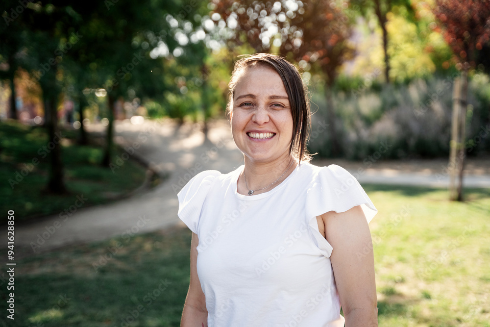 Casual colombian woman smiling in sunlit park with blurred tree background Casual colombian woman smiling in sunlit park with blurred tree background