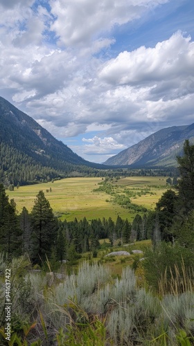 Mountain Valley with Green Meadow and Cloudy Sky.