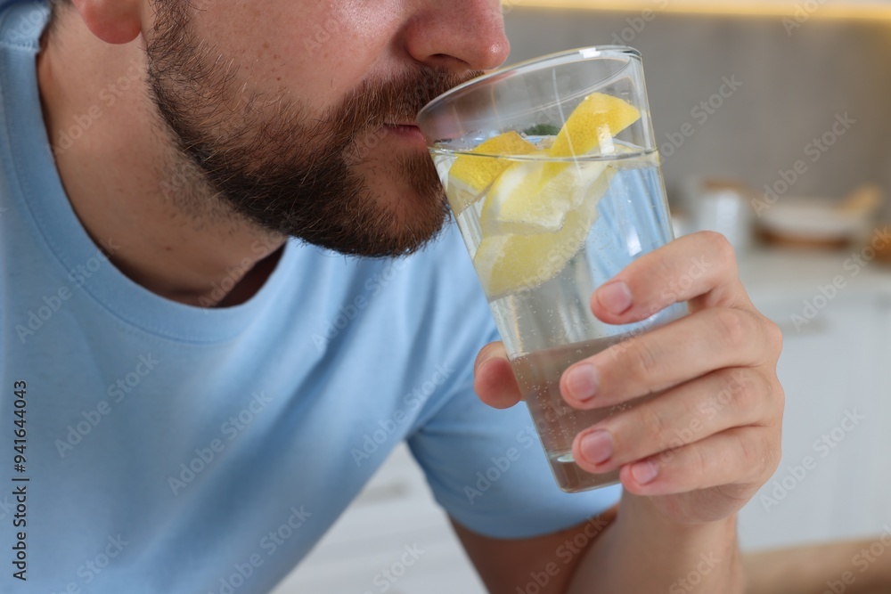 Man drinking water with lemon indoors, closeup Man drinking water with lemon indoors, closeup