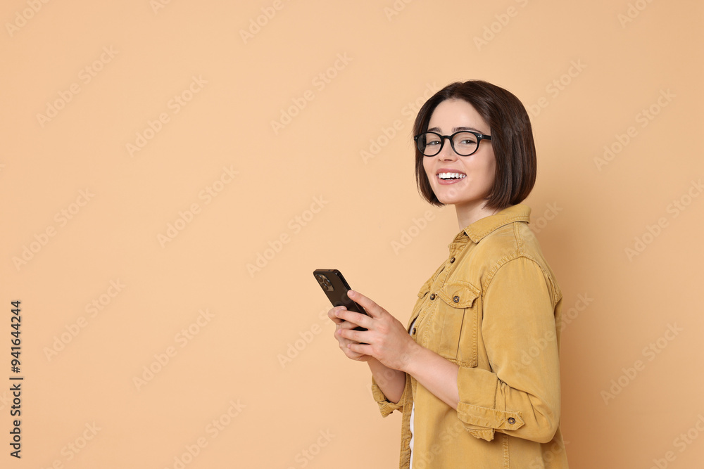 Smiling woman with smartphone on beige background. Space for text Smiling woman with smartphone on beige background. Space for text