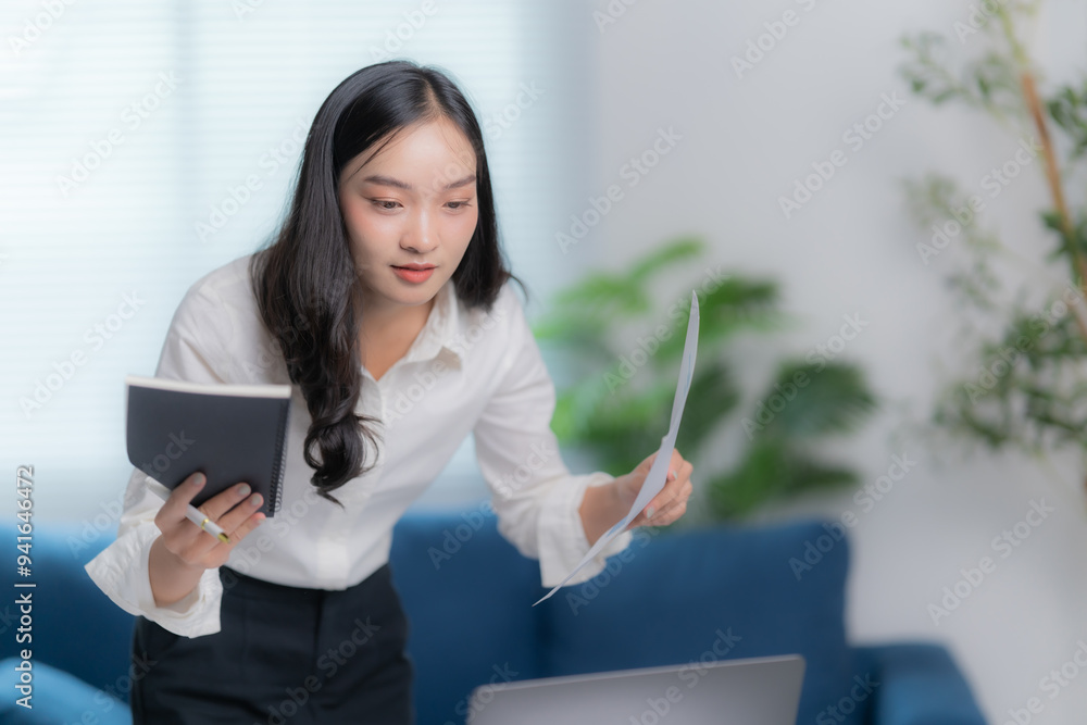 Asian businesswomen working in the office talking the phone, and checking the report Asian businesswomen working in the office talking the phone, and checking the report