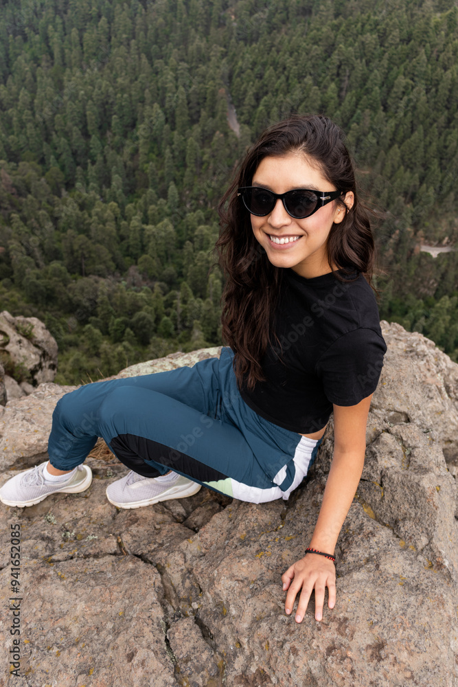 Young woman in sunglasses sitting on mountain top Young woman in sunglasses sitting on mountain top