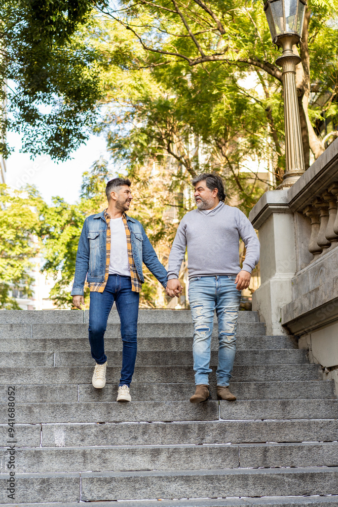 Gay couple happily walking down stairs in an urban park Gay couple happily walking down stairs in an urban park