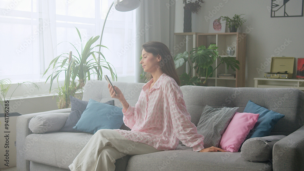 Woman sitting on comfortable sofa using smartphone Woman sitting on comfortable sofa using smartphone