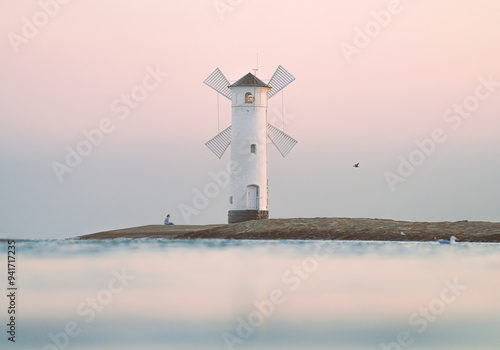 Mühlenbake - Stawa Młyny, a windmill-shaped lighthouse in Świnoujście, Poland, captured at sunset with serene pastel skies over calm waters.