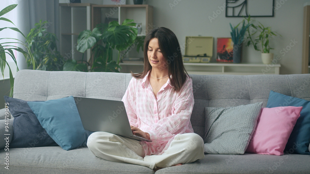 Woman working from home sitting on sofa using Woman working from home sitting on sofa using