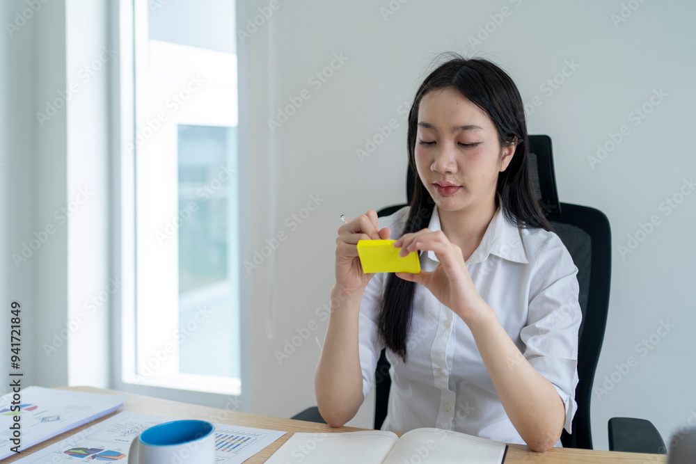 Young asian businesswoman writing on sticky notes while working at office desk Young asian businesswoman writing on sticky notes while working at office desk