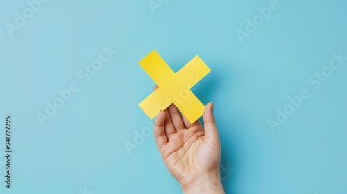 The hand holding yellow cross