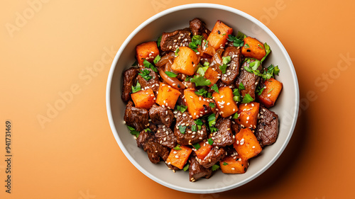 Hearty Korean autumn dish of stir-fried sweet potatoes with sesame seeds, caramelized onions, and tender beef, placed on a gradient background from warm brown to burnt orange 