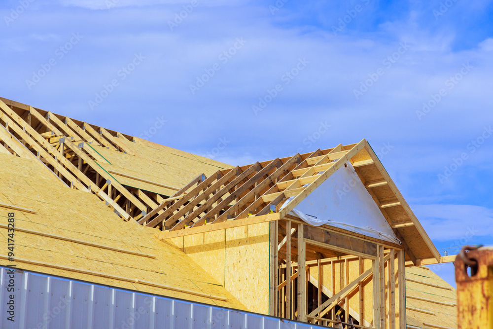 Obraz premium Placing plywood on wooden roofing trusses at assembled roof of house in construction