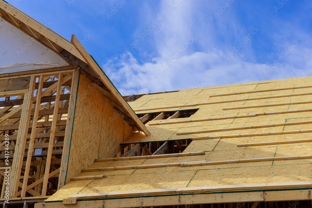 Plywood is installed on wooden roofing trusses at assembled roof of house in construction Plywood is installed on wooden roofing trusses at assembled roof of house in construction