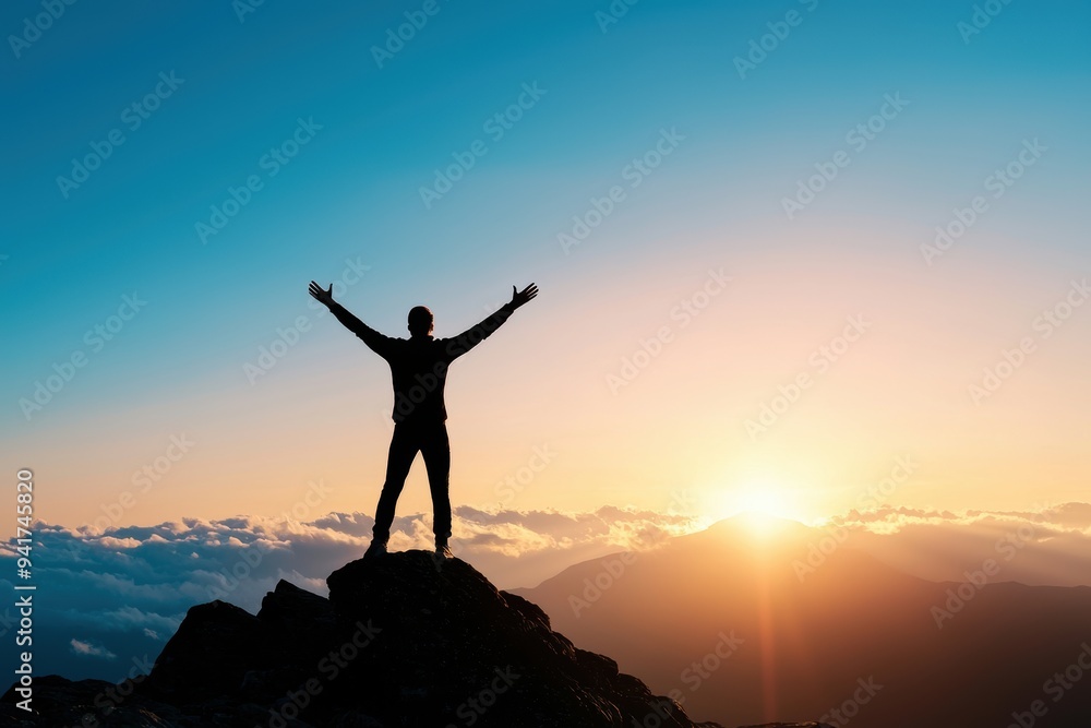 Silhouette of a man standing on a mountain top with arms raised at sunrise. The clear sky and distant mountains symbolize freedom and accomplishment. Silhouette of a man standing on a mountain top with arms raised at sunrise. The clear sky and distant mountains symbolize freedom and accomplishment.