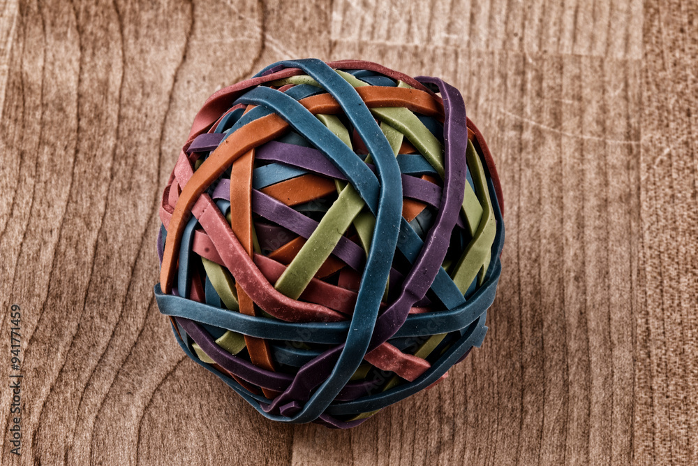 A rubber band ball lies on a table with wooden structures. A rubber band ball lies on a table with wooden structures.