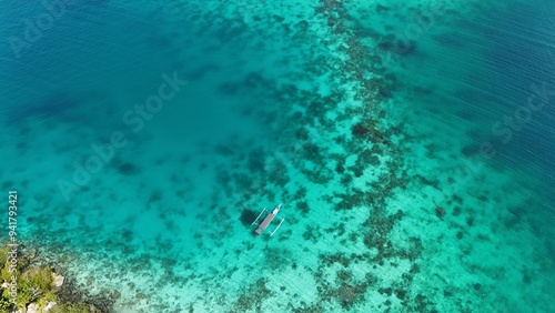 Fotografía Traditional indonesian boat floating on the ocean above a reef atoll with clear blue water ready for diving and snorkeling