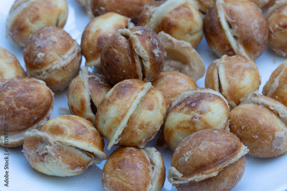 A bowl of delicious walnut-shaped cookies made with boiled condensed milk in a white plate, with a walnut-like appearance made in a cast mold.