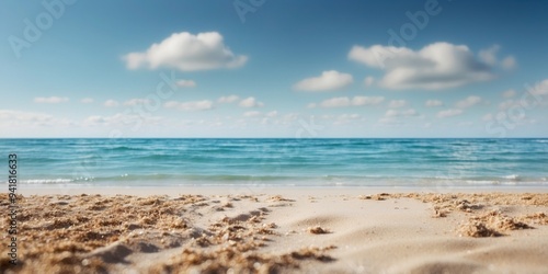 A sandy beach borders a body of water, with a blue sky dotted with clouds above.