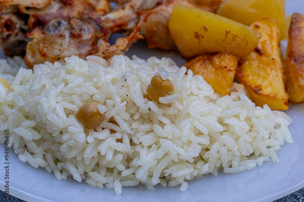Rice pilaf with chickpeas and fried chicken legs in the background.