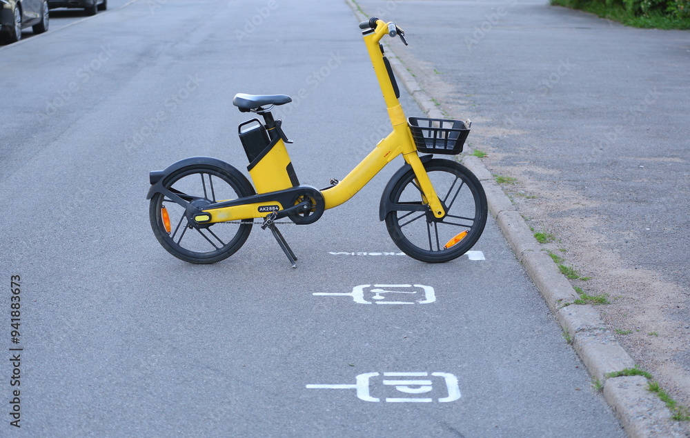 A yellow rental bike is parked in the parking lot A yellow rental bike is parked in the parking lot