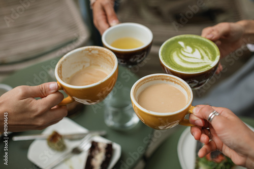 Four friends gather for breakfast in a cozy cafe enjoying buckwheat tea, cappuccino, matcha latte.