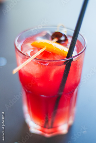 Sex on the Beach cocktail with slice of orange and a cherry with a straw photo