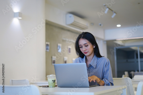 Concentrated attractive businesswoman working with laptop at modern office