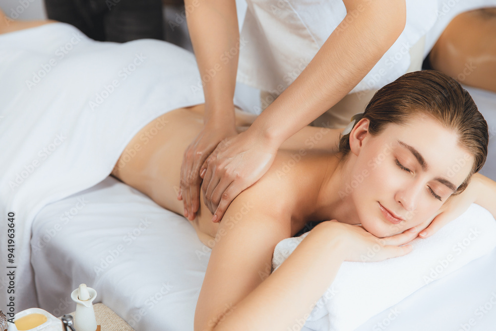 Caucasian couple customer enjoying relaxing anti-stress spa massage and pampering with beauty skin recreation leisure in day light ambient salon spa at luxury resort or hotel. Quiescent Caucasian couple customer enjoying relaxing anti-stress spa massage and pampering with beauty skin recreation leisure in day light ambient salon spa at luxury resort or hotel. Quiescent