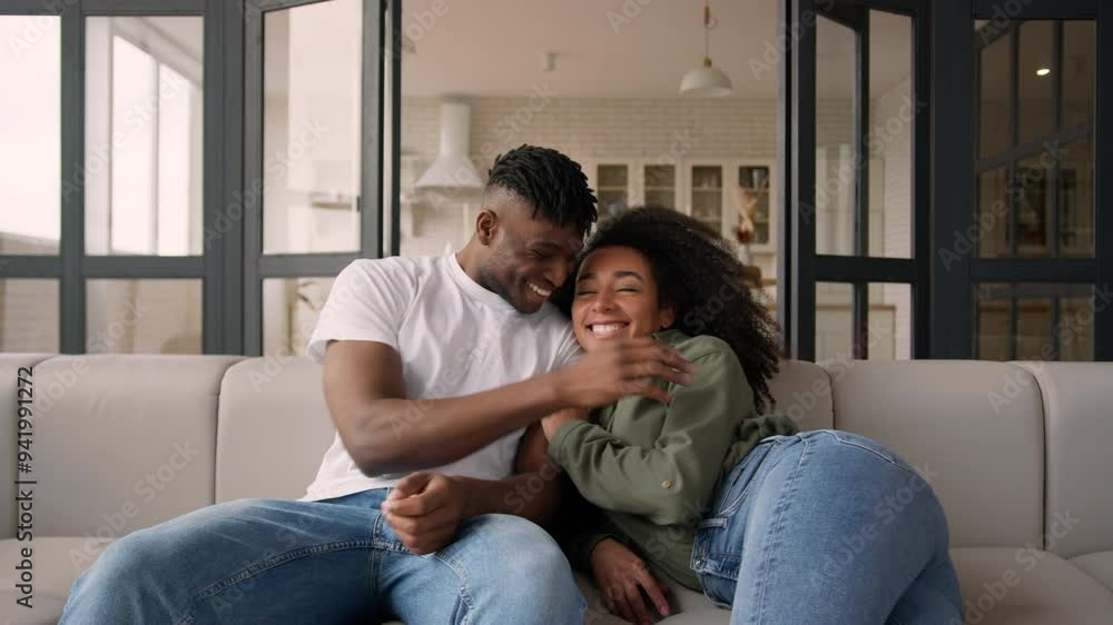 Happy couple African American ethnic family smiling woman man girl guy fall jump on couch jumping own home satisfied husband wife homeowners moving relocation casual weekend cuddle relax on cozy sofa Happy couple African American ethnic family smiling woman man girl guy fall jump on couch jumping own home satisfied husband wife homeowners moving relocation casual weekend cuddle relax on cozy sofa