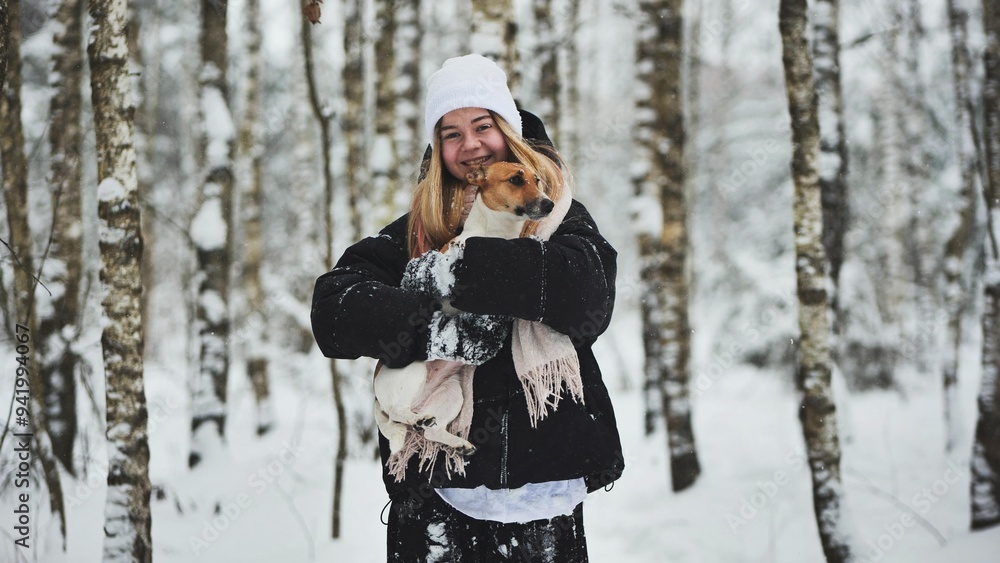 A girl cuddles a Jack Russell Terrier dog in the woods in winter. A girl cuddles a Jack Russell Terrier dog in the woods in winter.