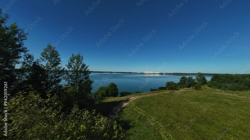 A beautiful panoramic view of Elektrenai Lake in Lithuania, with a clear blue sky and lush greenery surrounding the tranquil waters, perfect for nature lovers. High quality 4k footage A beautiful panoramic view of Elektrenai Lake in Lithuania, with a clear blue sky and lush greenery surrounding the tranquil waters, perfect for nature lovers. High quality 4k footage