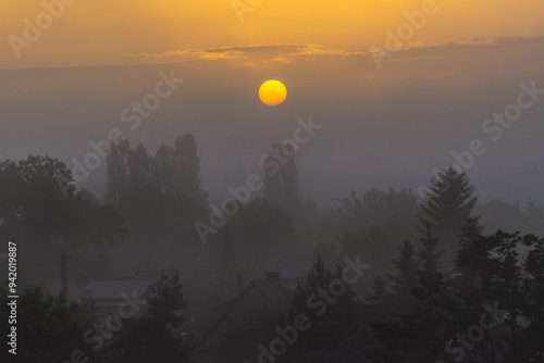 Mistyczny wschód słońca nad lasem i domami photo