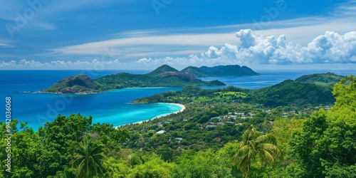 A beautiful view of a tropical island with a blue ocean in the background. The island is surrounded by mountains and has a small town on it. The sky is clear and the sun is shining brightly