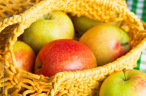 ripe red and green apples in a string bag close-up photo