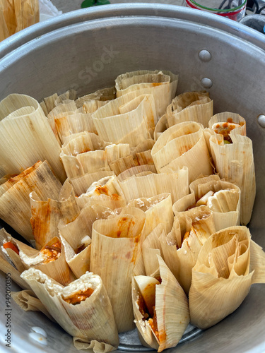 Uncooked beef tamales with red sauce inside steamer ready to be cooked.