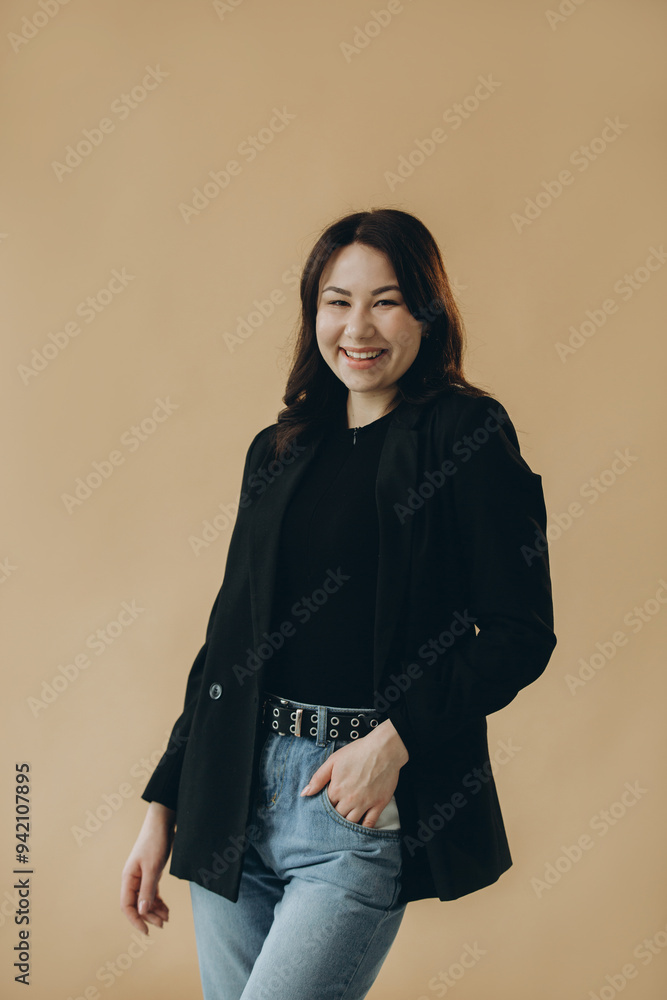 Fototapeta premium A stylish young brunette in a turtleneck and a jacket on a beige background.