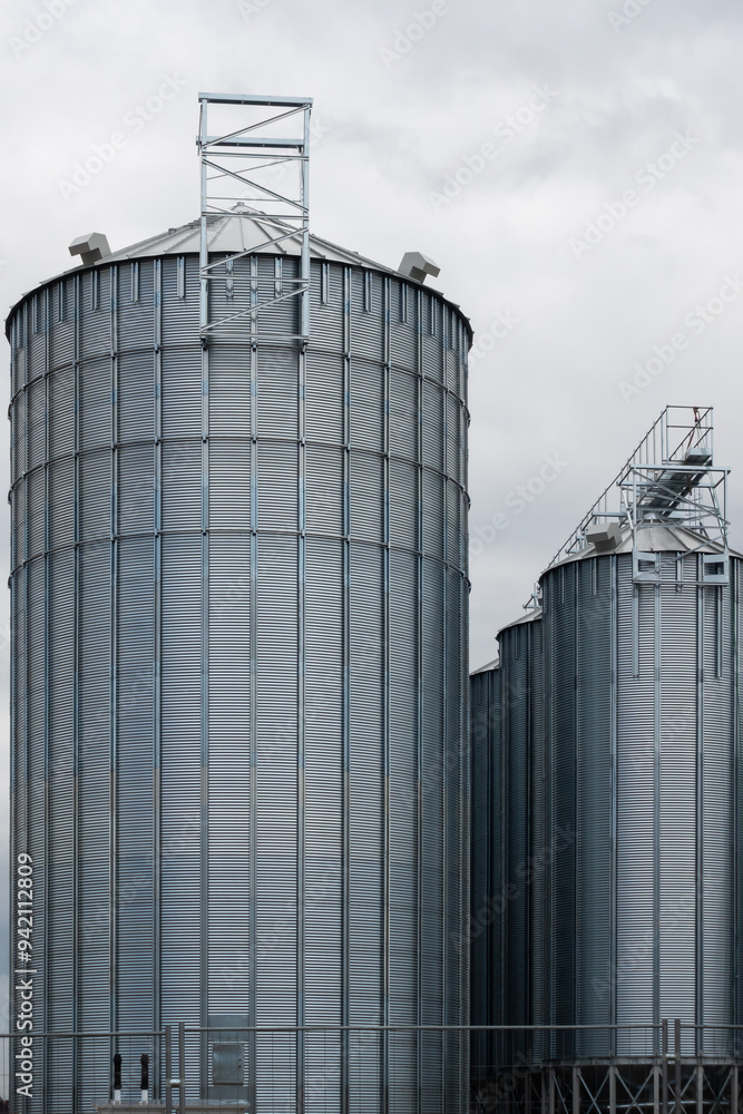 Steel grain silo against a dramatic, cloudy sky. Modern agriculture buildings photographed in the day .