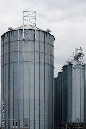 Obraz na płótnie Steel grain silo against a dramatic, cloudy sky. Modern agriculture buildings photographed in the day . w salonie