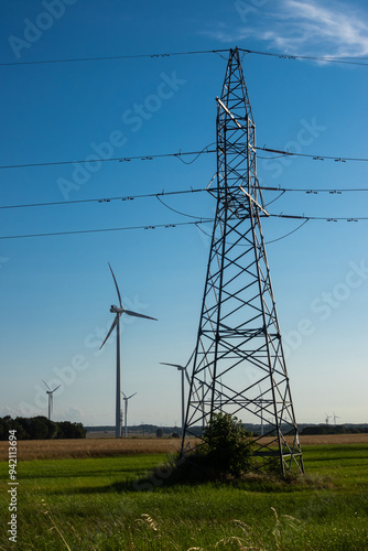 Obraz na płótnie Wind turbines and high voltage electric pylon against blue sky. Sun shining behind the turbines w salonie
